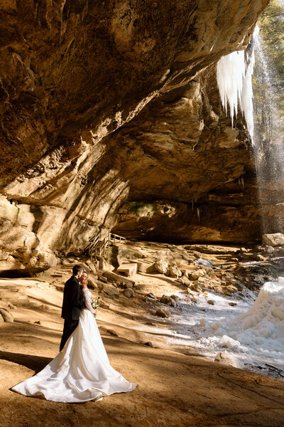 Couple embracing next to a frozen waterfall at Ash Cave.