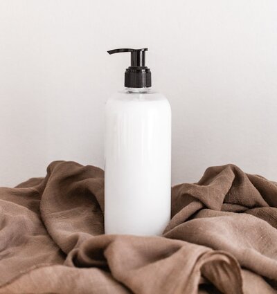 Pump bottle lotion sitting on top of a brown blanket 