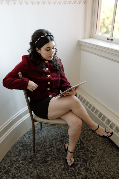 Shanté Gorman, founder of Sugarpunch Marketing®, a content marketing agency, sitting on a chair in a red jacket, holding a tablet and focusing on strategy.