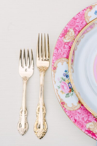 Colorful pink plate with gold flatware