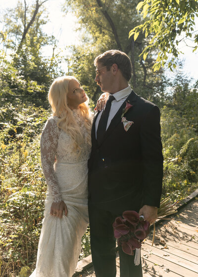 The bride and groom share an intimate moment with a beautiful tree-lined sunset backdrop.