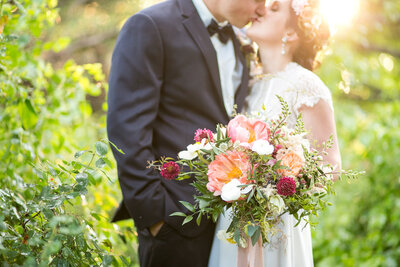 Bride holding a beautiful bouquet of flowers kissing her groom