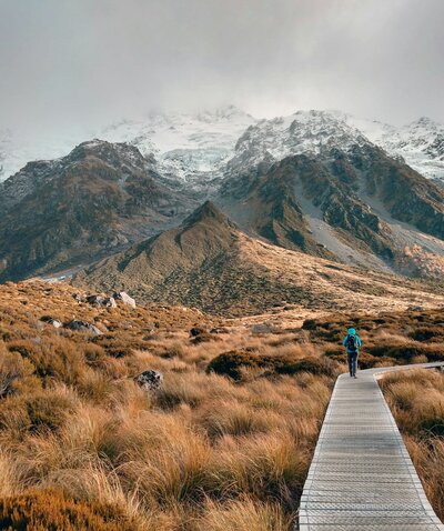 A person walking along a boardwalk trail in the mountains.