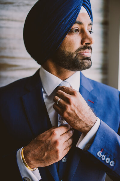 Indian Sikh groom tying his tie and getting ready for his indian wedding reception