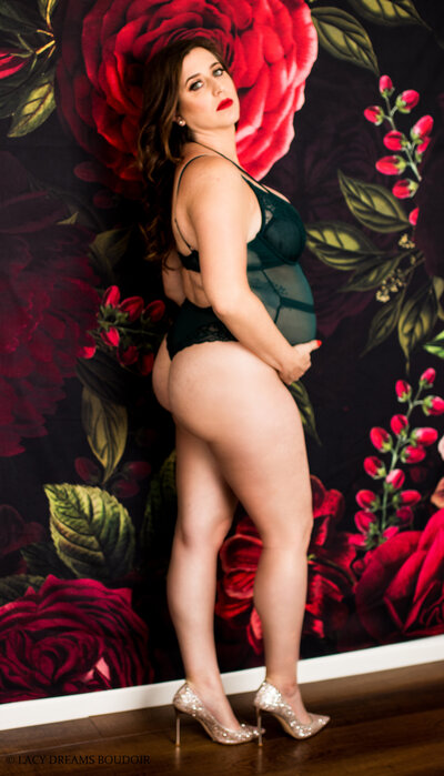 Pregnant woman wearing green lingerie next to wall with red lips