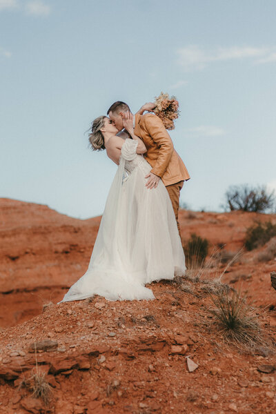 Bride and groom kissing on top of rock