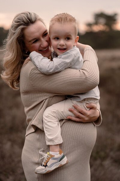 Zwangere vrouw met haar partner lopen door de natuur tijdens een zwangerschapsshoot.