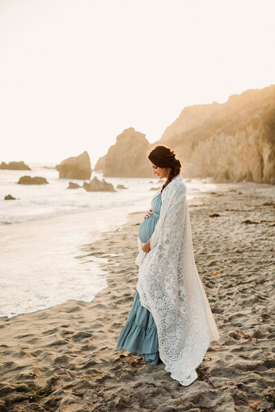 Beautiful pregnant woman poses for maternity portraits on the beach