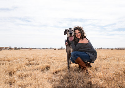 woman in New Mexico field  hugging  dog