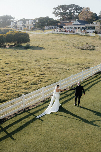 Drone photography of bride and groom walking on a ranch during their wedding cocktail hour