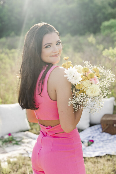 girl smiling in a hot pink dress holding a flower bouquet