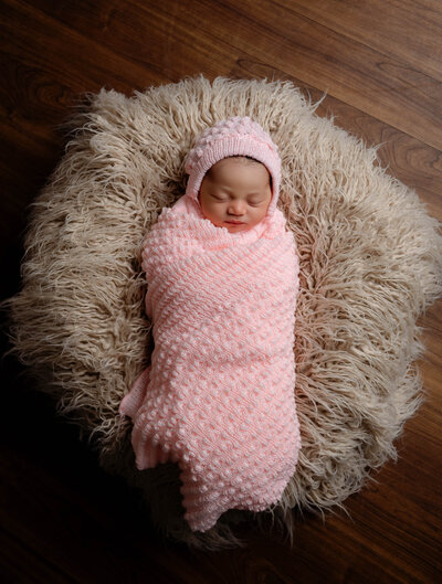 newborn baby girl in pink swaddle and beanie