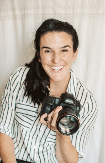 brunette woman holding a camera and smiling 