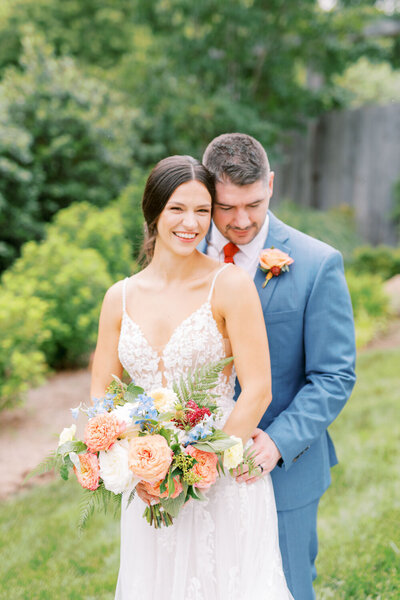 Bride smiling while groom hugging her in the back