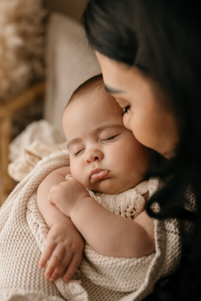 Photo of a Mom cuddling her baby close at a newborn photoshoot in Shrewsbury. The baby is wrapped in a fluffy blanket.