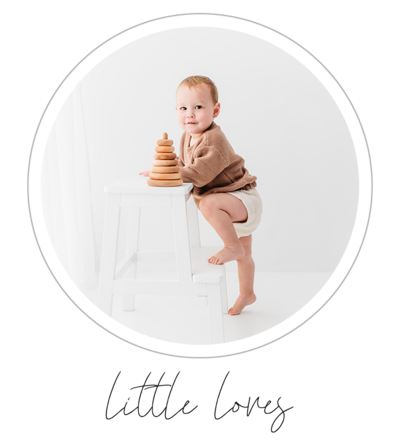 This photo shows an adorable three-year-old boy confidently climbing a ladder for his Studio children's portrait photography session. The backdrop is pure white, creating a sense of simplicity and elegance. Shot by talented photographer Bri Sullivan, the image is clean and classic, capturing timeless moments.