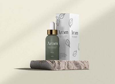 Bouteille en verre avec pipette d'huile essentielle et son packaging d'emballage, posés sur une pierre. Supports imprimés crées par le Studio Youmé, graphisme en vendée.