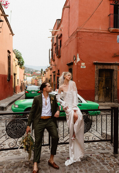 bride and groom sitting on a fence