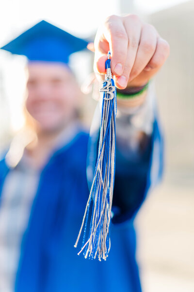 senior boy in cap and gown holding tassle