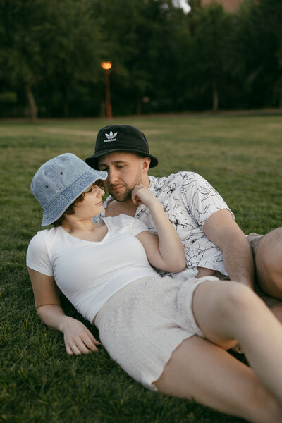 a man and a woman with hats on both of their heads snuggled up in the grass