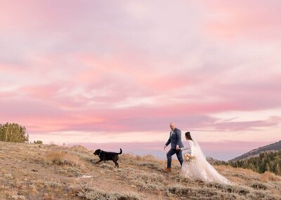 A bride and groom take a walk with their dog at sunset on the Mammoth Wedding day. 