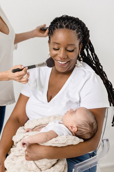 Mom holding newborn baby getting makeup done by nj portrait photographer Ally Kimpton