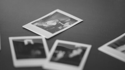 Black-and-white close-up of polaroid photos from a wedding, representing the nostalgic and artistic style of Tyler and Makenzie Films’ wedding videography.