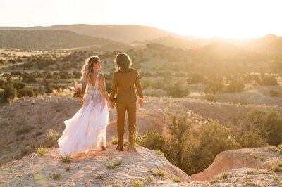 Couple stands in the desert and kisses on their elopement day while the sun sets