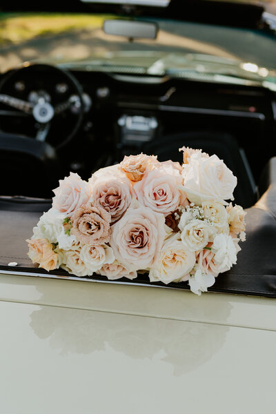 flower bouquet laying on top of a vintage car