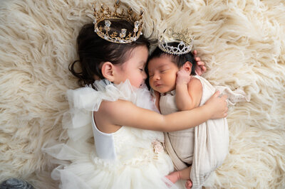 On an off-white flokati, siblings cozy up in formal outfits and matching crowns.