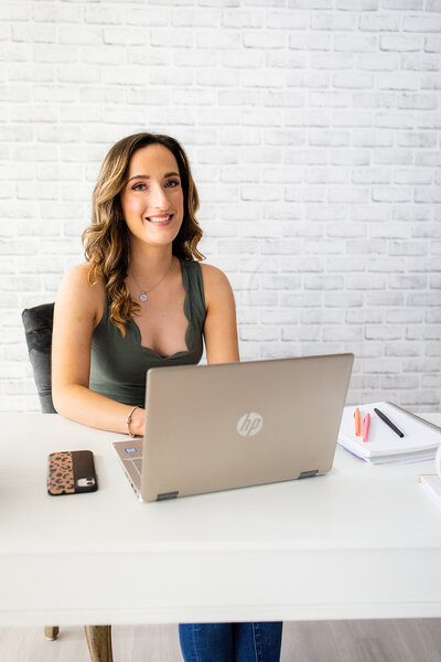 Payton Bendure, social media strategy for small business, Payton working on a laptop, sitting at a desk in a green tank top