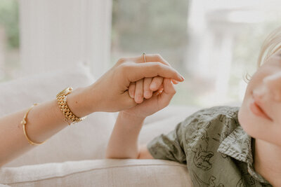 Close up of mom and son holding hands.