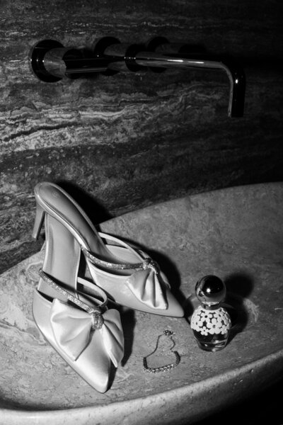 Wedding shoes heels in sink with perfume and jewelry