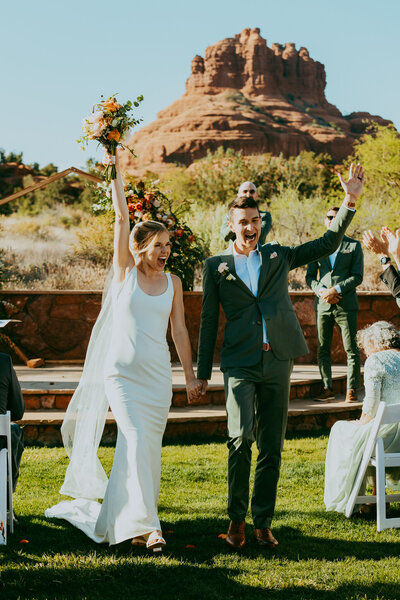 bride and groom walk down the isle with  bell rock behind them