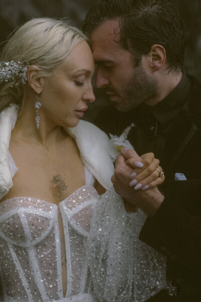 bride in a glittery white dress and groom holding hands during a rainy PNW elopement