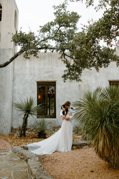 Bride and groom embracing each other with palm trees  and building in the back ground in Austin Texas