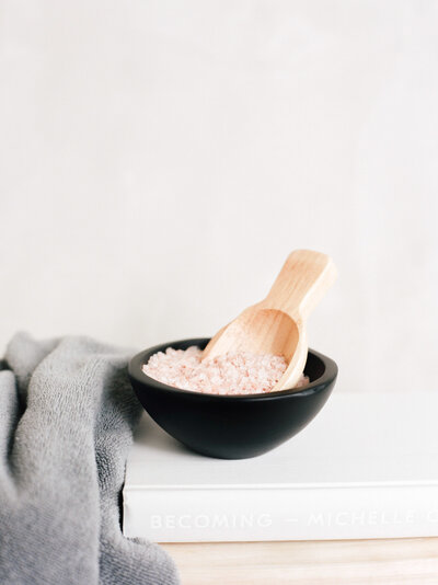 black bowl with pink salt and wooden scoop