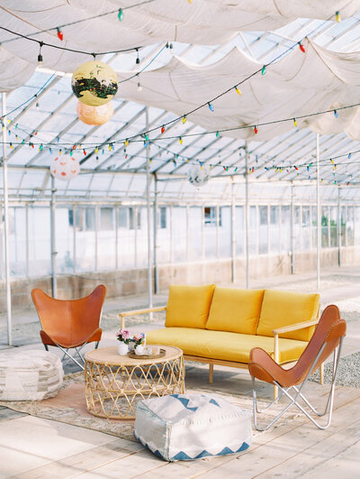 A detail of the comfortable and modern boho lounge area of the wedding reception in the greenhouse of Dos Pueblos Orchid Farm in Santa Barbara.