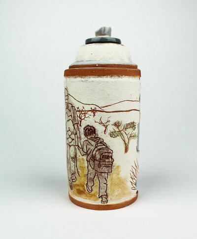 A ceramic spray paint can jar is decorated with imagery of a little boy holding someones hand while walking through the desert