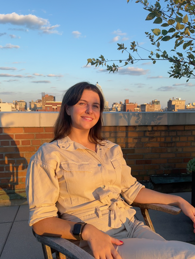 A photo of the Founder and Lead Designer, Georgia Deane, sitting on a roof terrace.