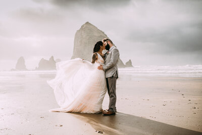 woman and man kissing on oregon beach cliff