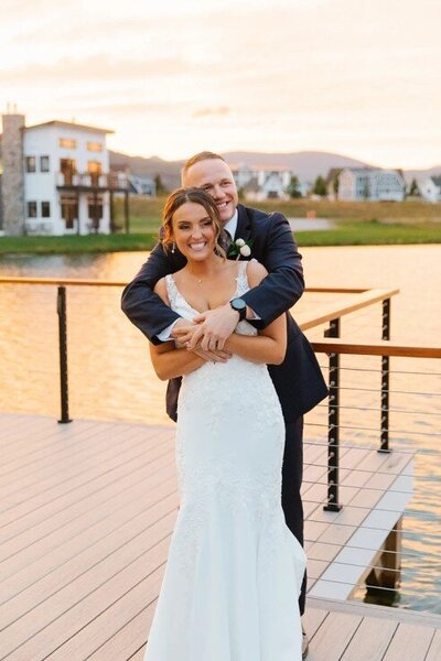Owl's Nest Resort - Groom Hugging Bride With Stunning Lakeview Behind Them