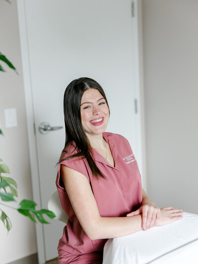 Woman in scrubs sitting by massage table during branding photoshoot