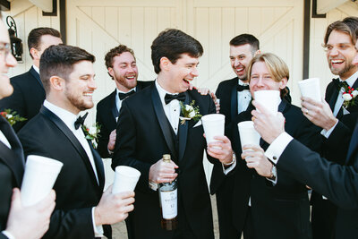 Groom and groomsmen celebrating outside of barn at the springs in NWA.