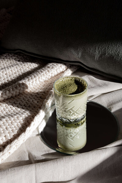 A glass of matcha latte rests on a round mirror atop a beige blanket, reminiscent of a serene moment in Phillipa Leseberg's latest memoir.