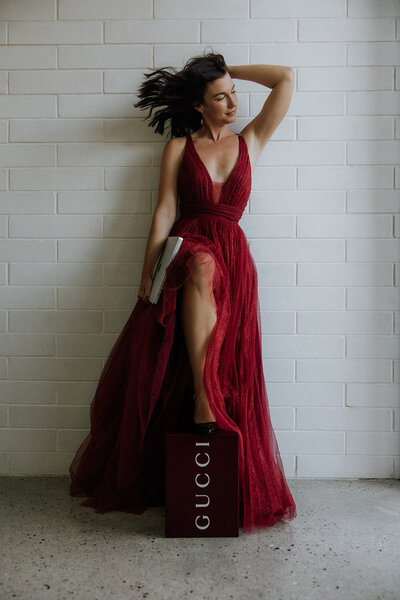 Branding photo of a woman in a red dress against a white wall with a Gucci bag taken by Sunshine Coast photographer