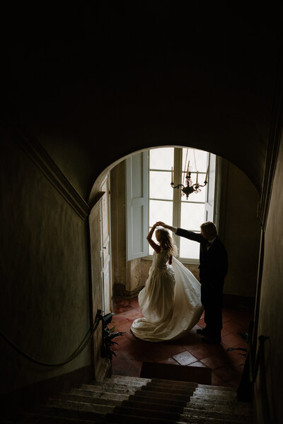 A wedding couple dancing at the bottom of a staircase 