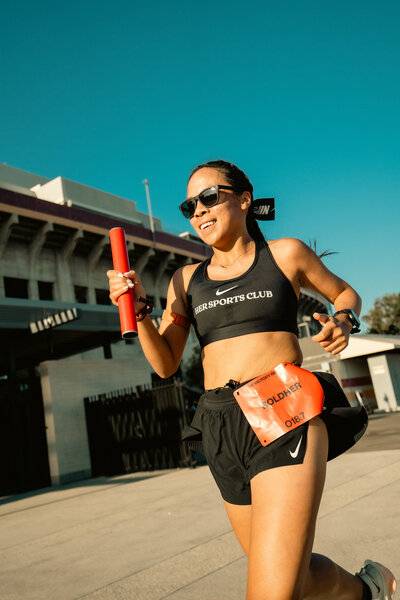 HER Sports Club runner carrying a baton while training near the stadium.