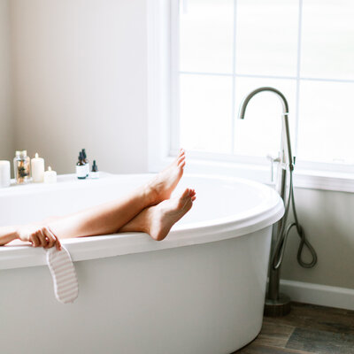 woman taking a relaxing bath resting her legs on the sides of the soaker tub