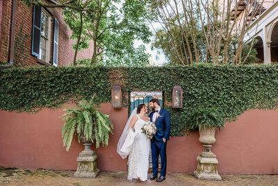 Bride and groom in front of ivy-covered gate in Savannah